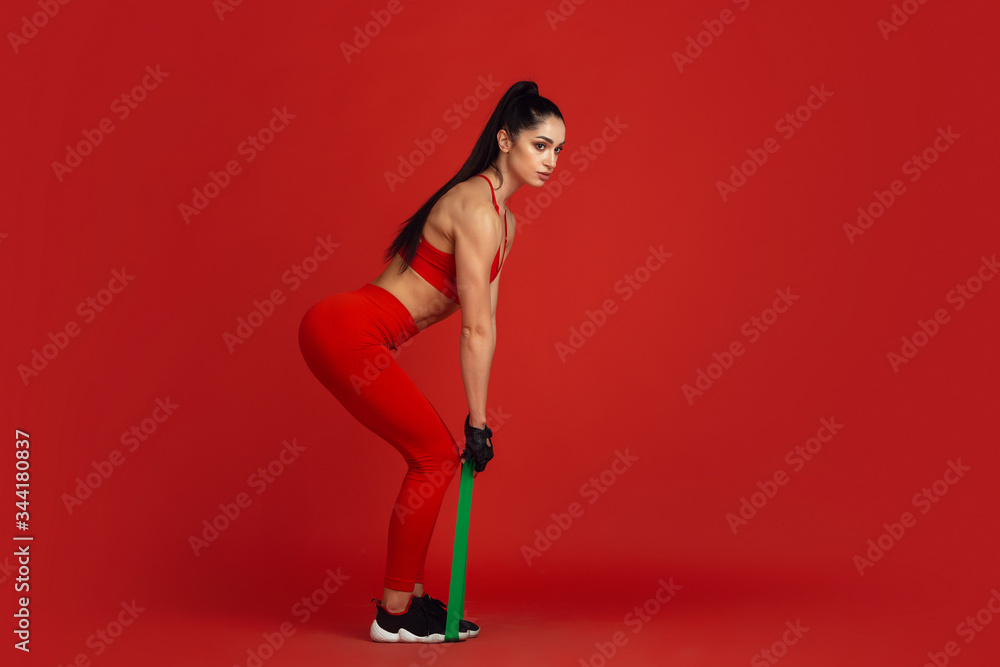 Sit ups. Beautiful young female athlete practicing in studio, monochrome red portrait. Sportive fit brunette model with elastics. Body building, healthy lifestyle, beauty and action concept. Sit ups. Beautiful young female athlete practicing in studio, monochrome red portrait. Sportive fit brunette model with elastics. Body building, healthy lifestyle, beauty and action concept.