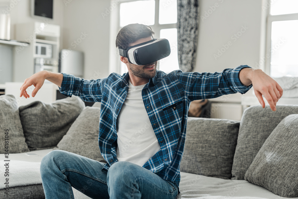 Smiling man using virtual reality headset on couch