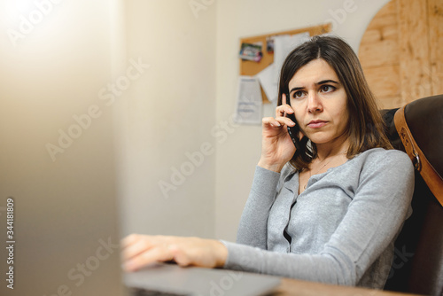 woman talking on the phone while working on computer in desk office