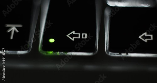 Pressing caps lock on backlit illuminated laptop computer keyboard at night