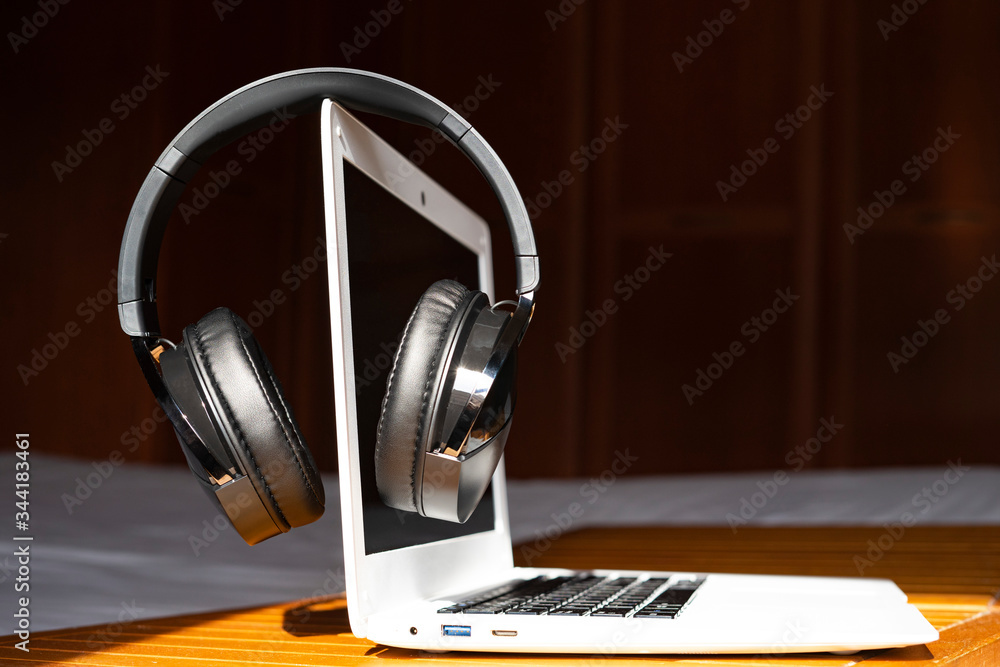 Music headphones on top of a computer.