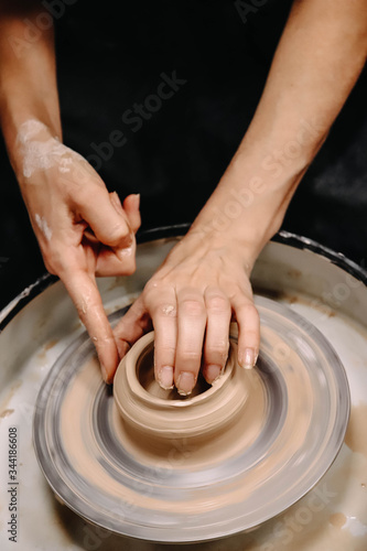 Hands of a potter with manicure at work close-up. Photo above