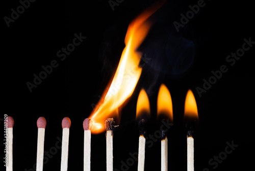 Group Of Matches Lit In Row Burning In Chain Reaction with Black Background.
