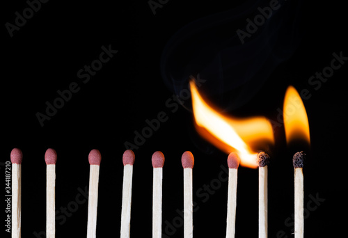 Group Of Matches Lit In Row Burning In Chain Reaction with Black Background.