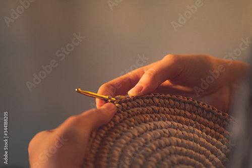 Round raffia crochet panno in female hands. Handcraft, hobby concept: making a wall hanging and a crochet hook photo