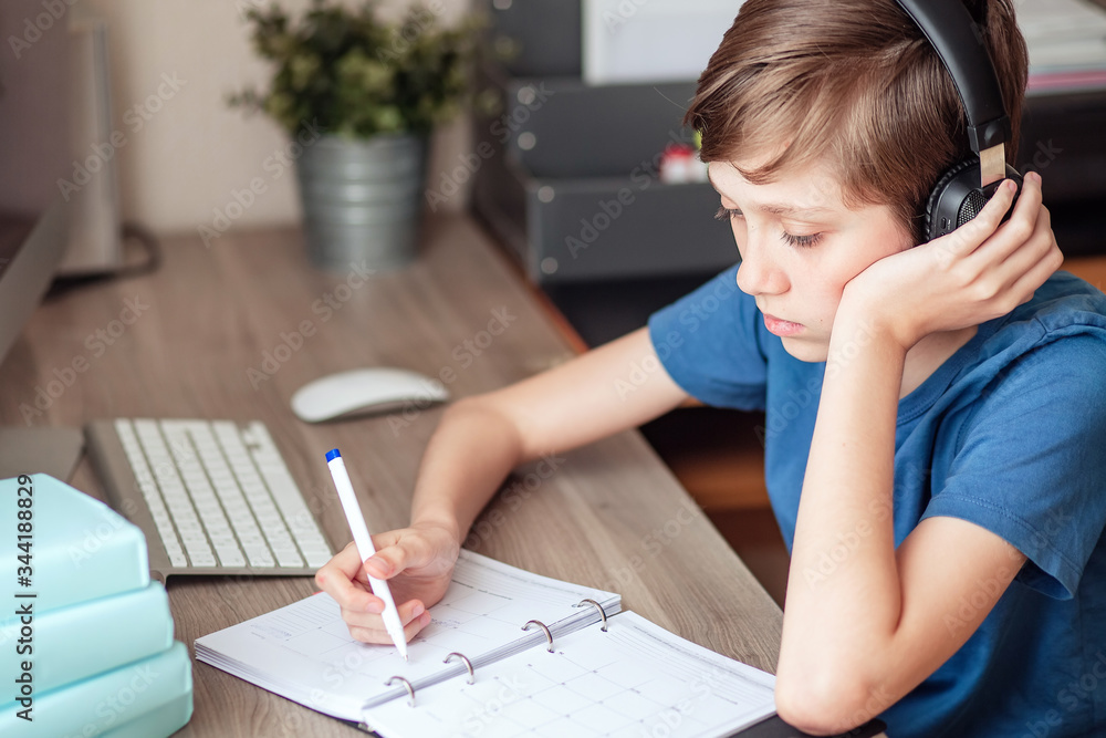 A teenage boy does homework, learns using a computer. Distance learning online. A child in quarantine in isolation learns independently at home. A teenage boy does homework, learns using a computer. Distance learning online. A child in quarantine in isolation learns independently at home.