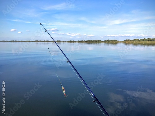 Tela Fishing Rod On Calm Lake Against Blue Sky
