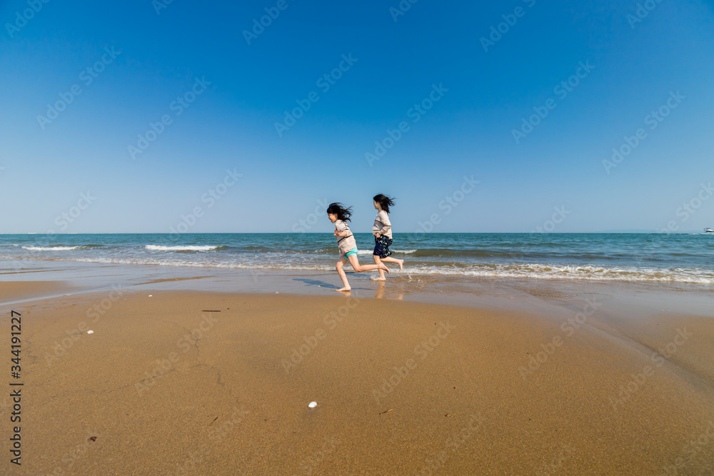 海岸で海遊ぶをしている子供姉妹