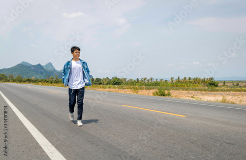 An Asian man is walking alone on the road of thailand countryside.