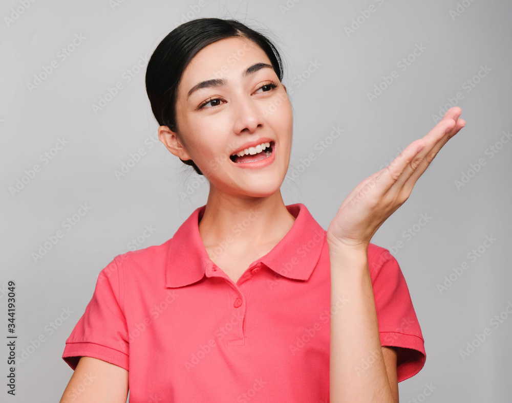 young beautiful asian woman wore pink t shirt, Showed guide expression ,smile and suggest on gray background young beautiful asian woman wore pink t shirt, Showed guide expression ,smile and suggest on gray background