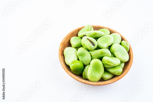 Fresh broad beans in a saucer on white background