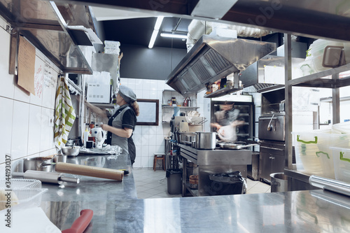 Behind the scenes of brands. The chef cooking in a professional kitchen of a restaurant meal for client or delivery. Open business from the inside. Meals during the quarantine. Hurrying up, motion.