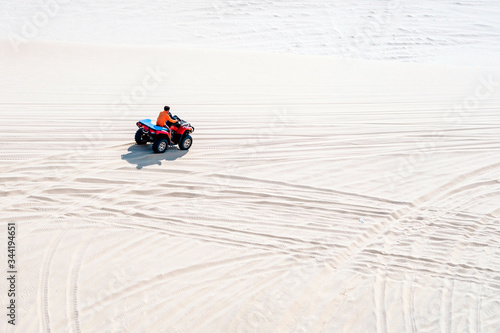 Tourist enjoy riding the quad bike or powerful fast off-road four-wheel drive ATVs at white sand dunes in Mui Ne, Vietnam.