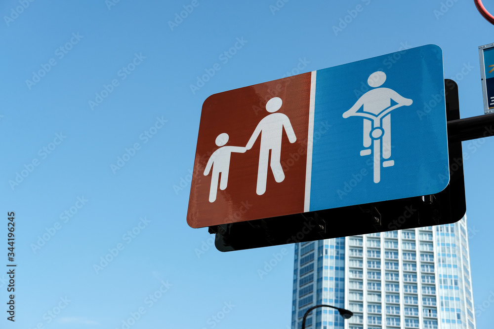 The Adult symbol walks the hand of children signboard and bike lane signboard with blue sky backgrounds The Adult symbol walks the hand of children signboard and bike lane signboard with blue sky backgrounds