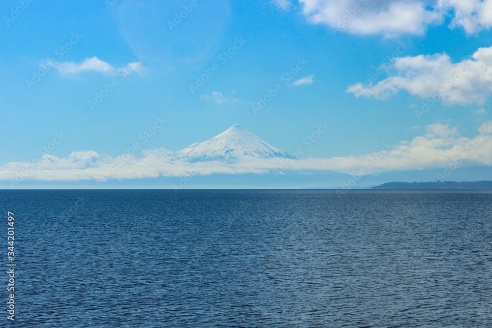 Beautiful snowy mountain in the distance seen from the calm water of the lake. Beautiful snowy mountain in the distance seen from the calm water of the lake.