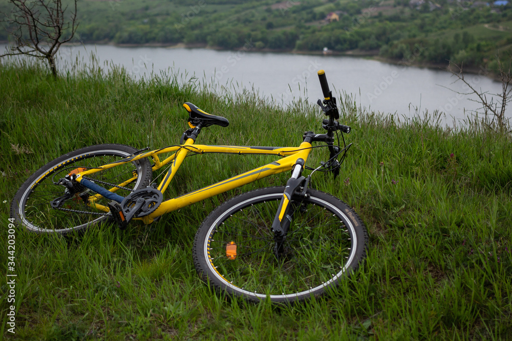 Yellow bicycle on green grass by the river