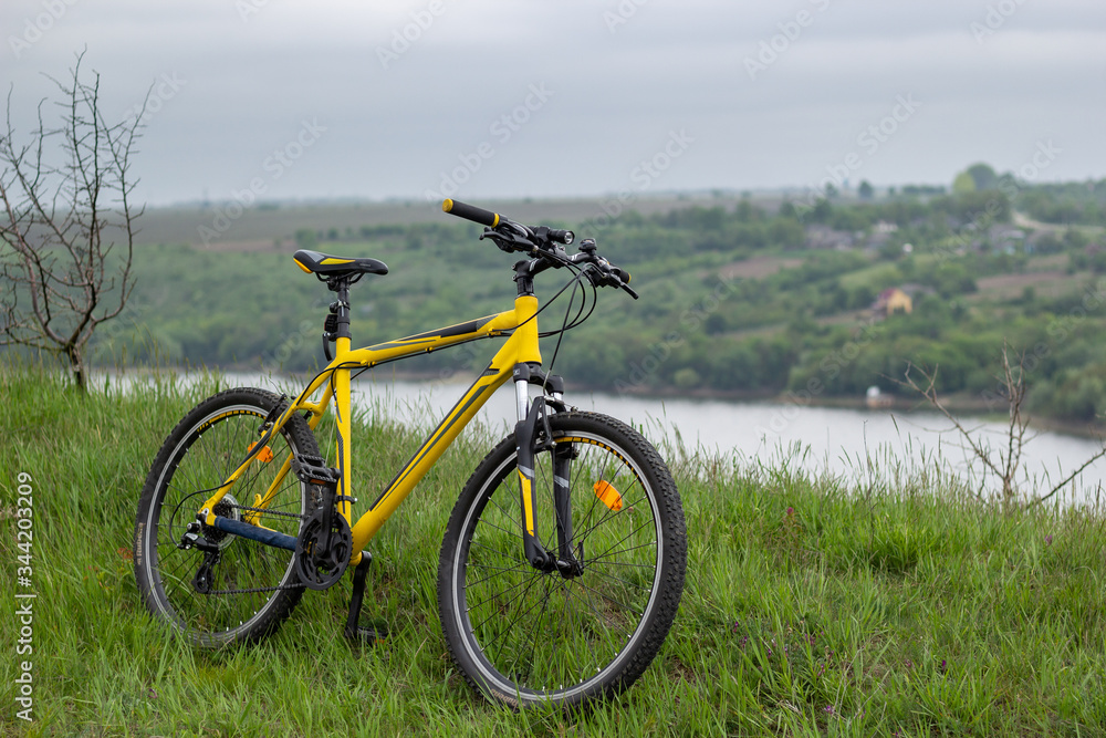 Yellow bicycle on green grass by the river Yellow bicycle on green grass by the river