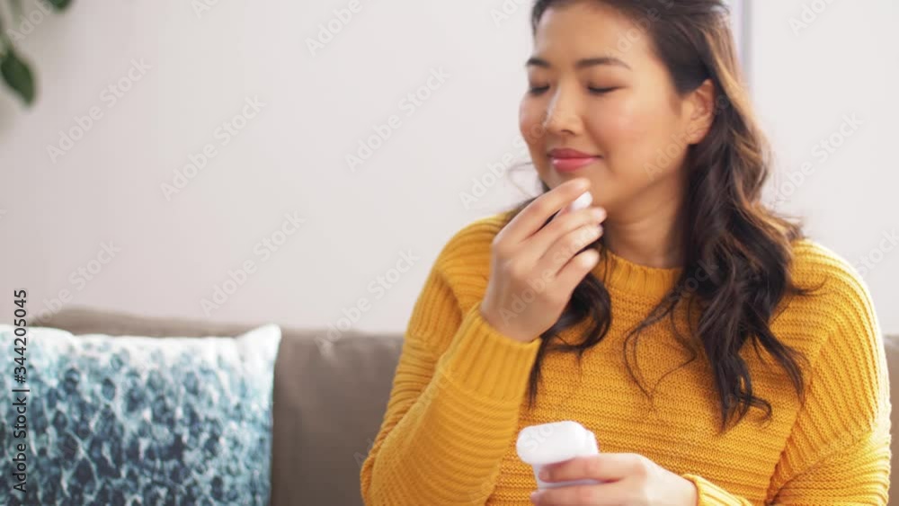 people, technology and leisure concept - happy asian young woman with wireless earphones and smartphone listening to music at home people, technology and leisure concept - happy asian young woman with wireless earphones and smartphone listening to music at home