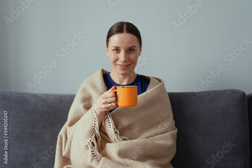 Happy woman recovered from a flu enjoying a cup of tea wrapped in a warm blanket Fototapet