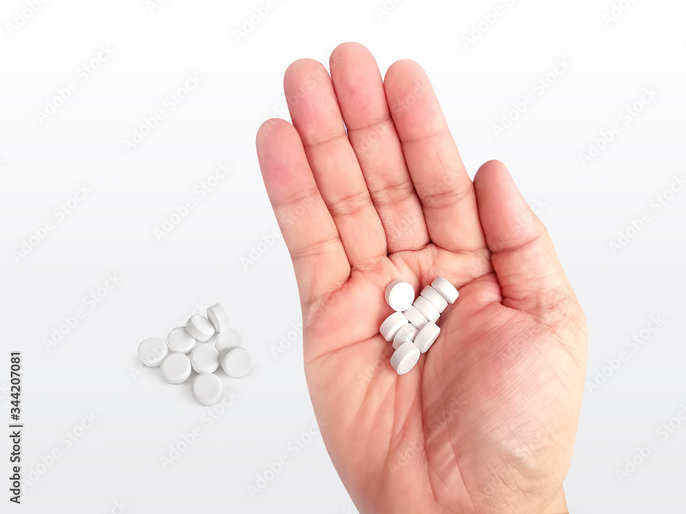 A handful of white pills in hand on a white background