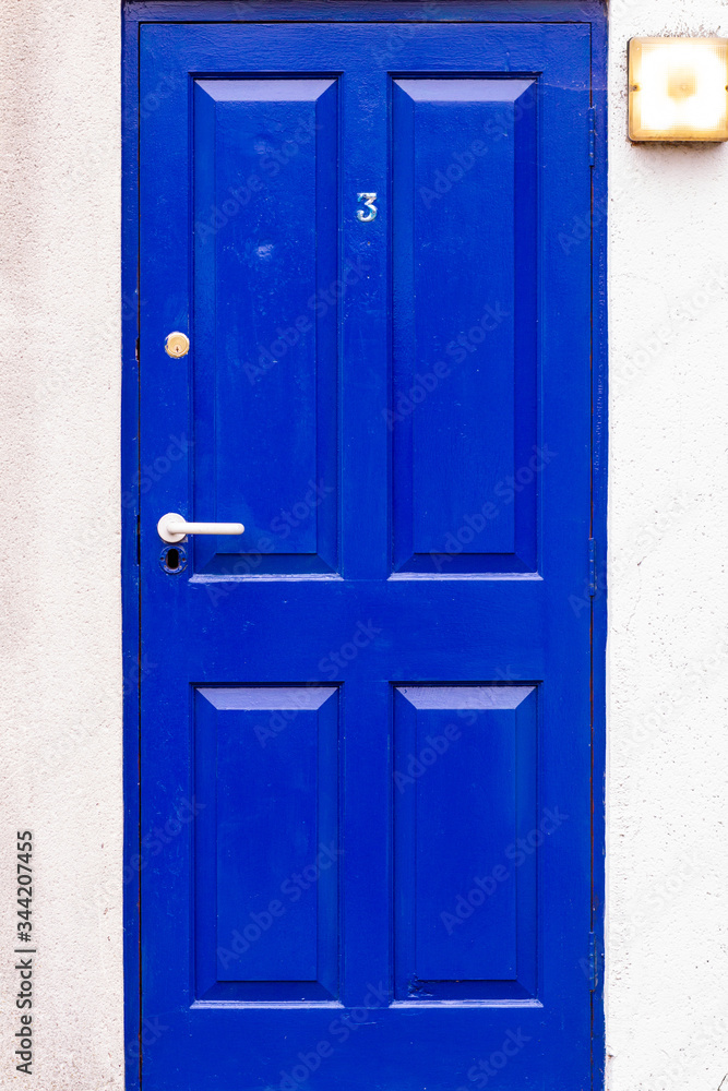 Blue wooden front door with the number 3 in London, UK