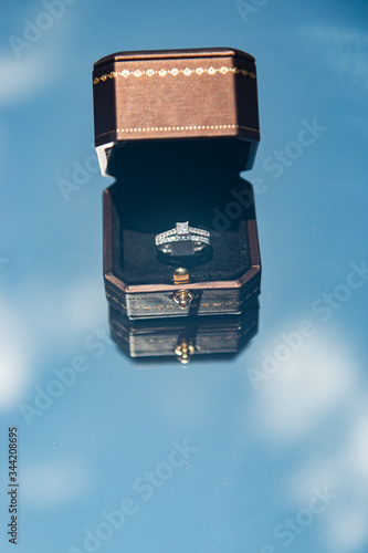 A bride's diamond wedding ring in a black box on a blue sky background