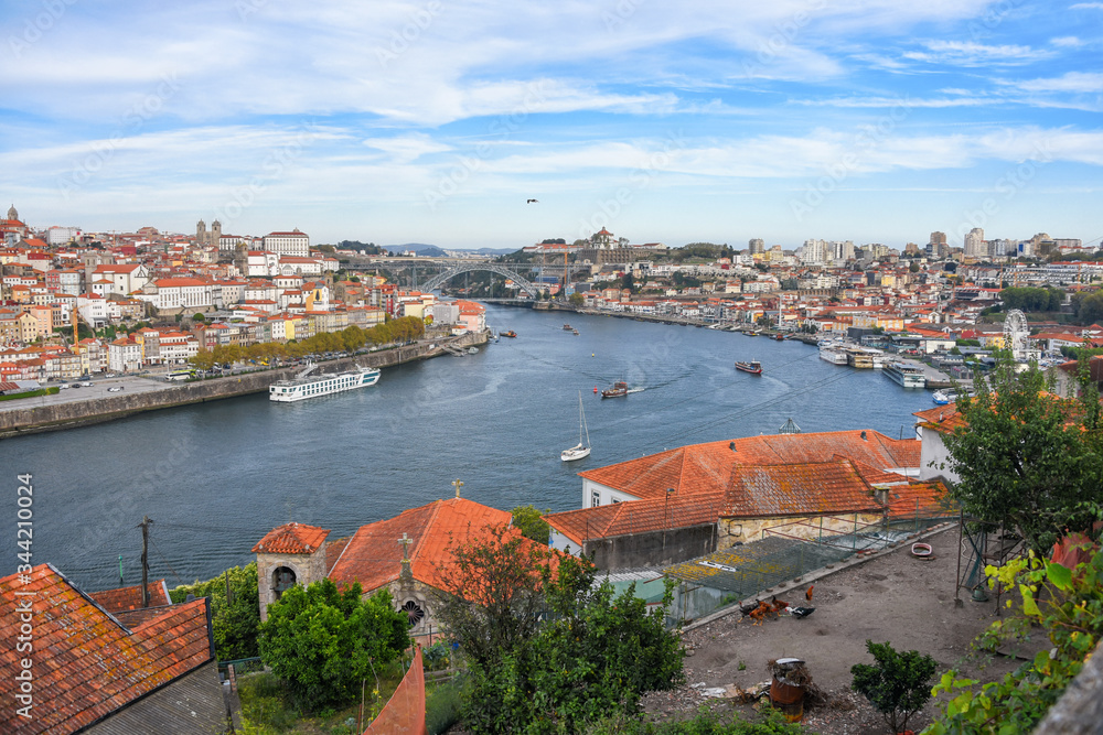 Porto, Portugal old town ribeira aerial promenade view with colorful houses, traditional facades, old multi-colored houses with red roof tiles, Douro river and boats. Aerial cityscape image of Porto