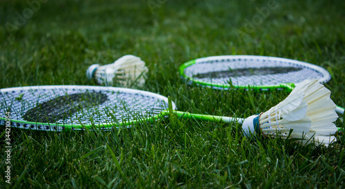 Two badminton rackets and shuttlecocks lying on green grass