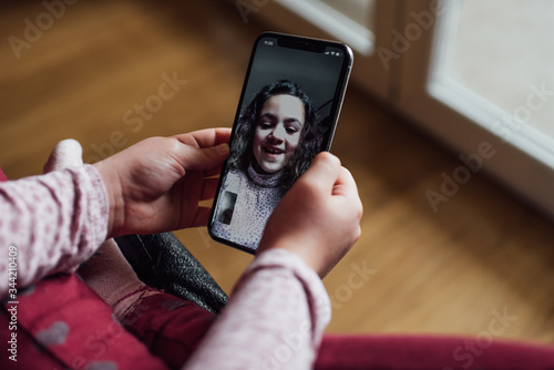 A young Spanish girl holds a mobile phone with which she is making a video call with her family