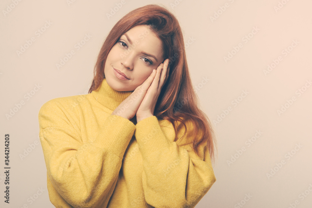 Serious sleepy young woman. Beautiful dreamy young woman holding hands near head and looking at camera. Dream concept Serious sleepy young woman. Beautiful dreamy young woman holding hands near head and looking at camera. Dream concept
