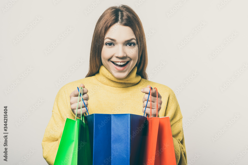 Excited young woman with shopping bags. Cheerful young woman holding colorful paper bags and smiling at camera. Shopping concept Excited young woman with shopping bags. Cheerful young woman holding colorful paper bags and smiling at camera. Shopping concept