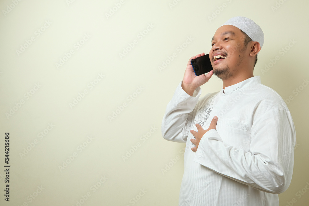 Asian Muslim man looks happy when receiving a call from his brother Asian Muslim man looks happy when receiving a call from his brother