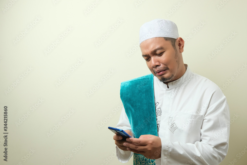 Asian Muslim man looks sad while receiving phone Asian Muslim man looks sad while receiving phone