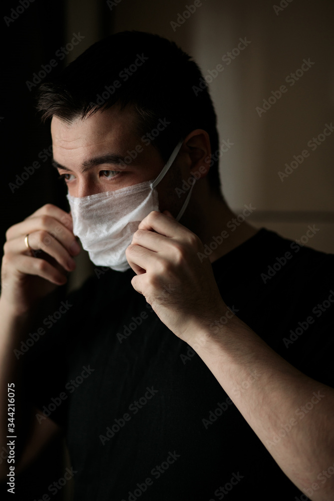 man straightens a medical mask with his hands
man straightens a medical mask with his hands