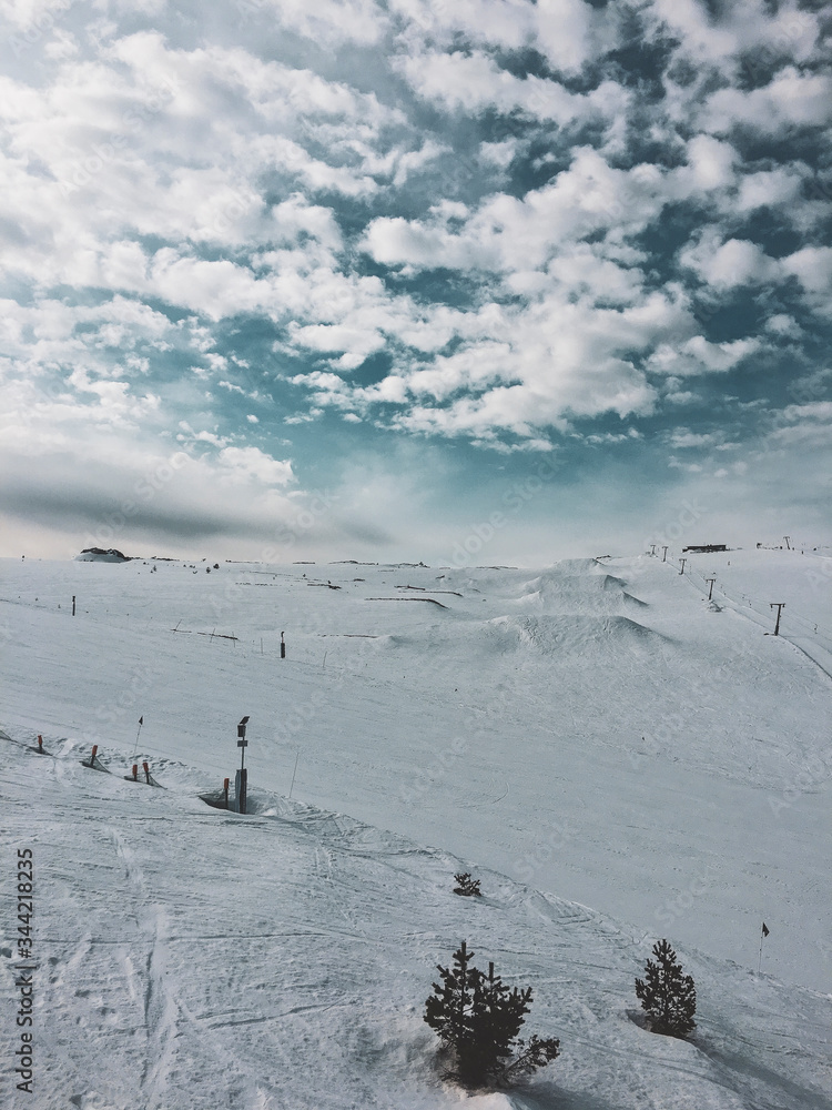 mountain top with snow, sky, clouds, ski-run and ski lift
