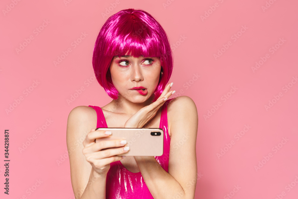 Image of young upset girl wearing wig playing video games on cellphone Image of young upset girl wearing wig playing video games on cellphone