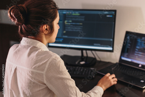 The programmer girl works at the computer. Information technology by the hands of women. Women in business. The girl works from home.