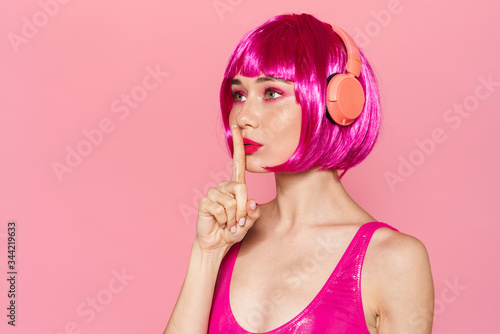Image of woman gesturing silence sign and using wireless headphones