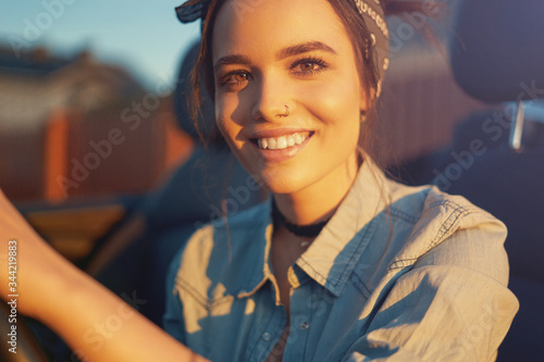 Young beautiful girl sitting in cabrio car on sunset wait for friends and think about perfect weekend so cute smiling to you