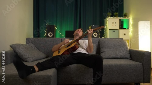 a man plays guitar sitting on the couch