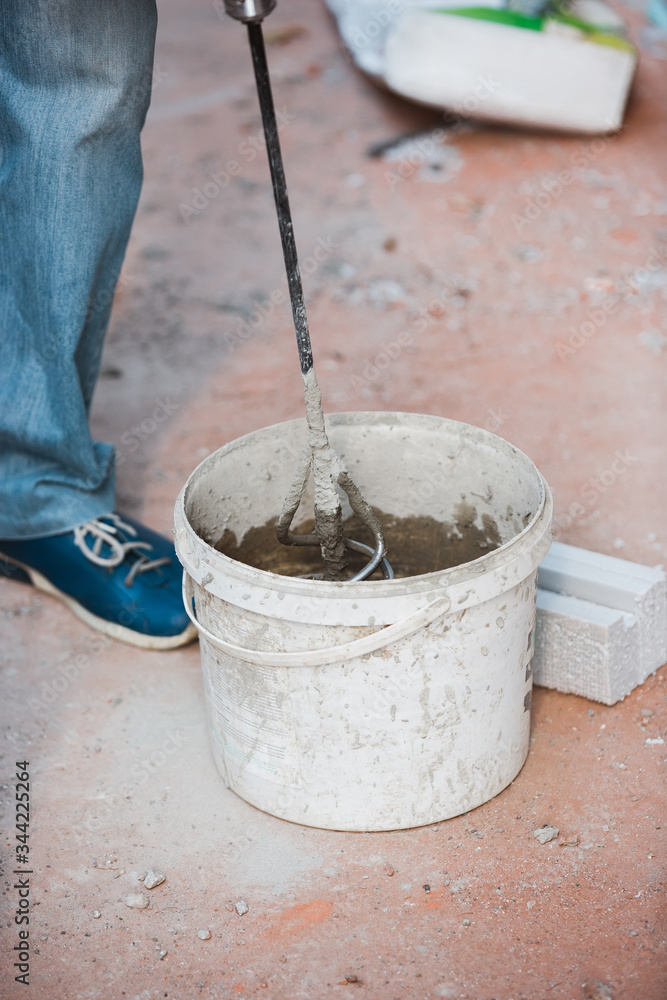 Closeup of repairman in uniform, professional builder working using construction equipment. Process of building, apartment renovation, repairing, building. Coloring, measuring, preparing the base.