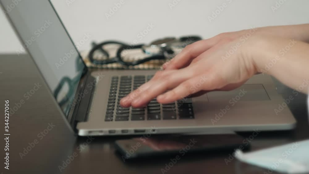 Woman sitting at desk and connecting with her laptop, she is working and typing on the keyboard, hands close up Woman sitting at desk and connecting with her laptop, she is working and typing on the keyboard, hands close up