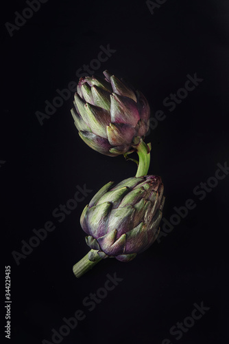 Fotografie Fresh raw artichokes on black background