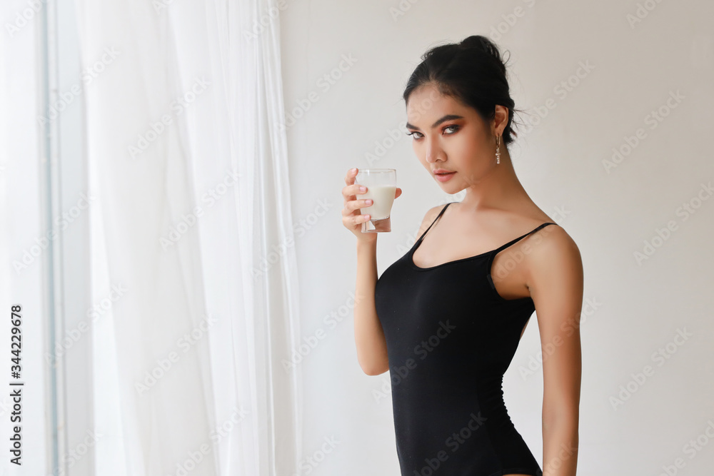 portrait of attractive and beautiful asian woman in sportswear with a glass of milk with white background in studio house portrait of attractive and beautiful asian woman in sportswear with a glass of milk with white background in studio house