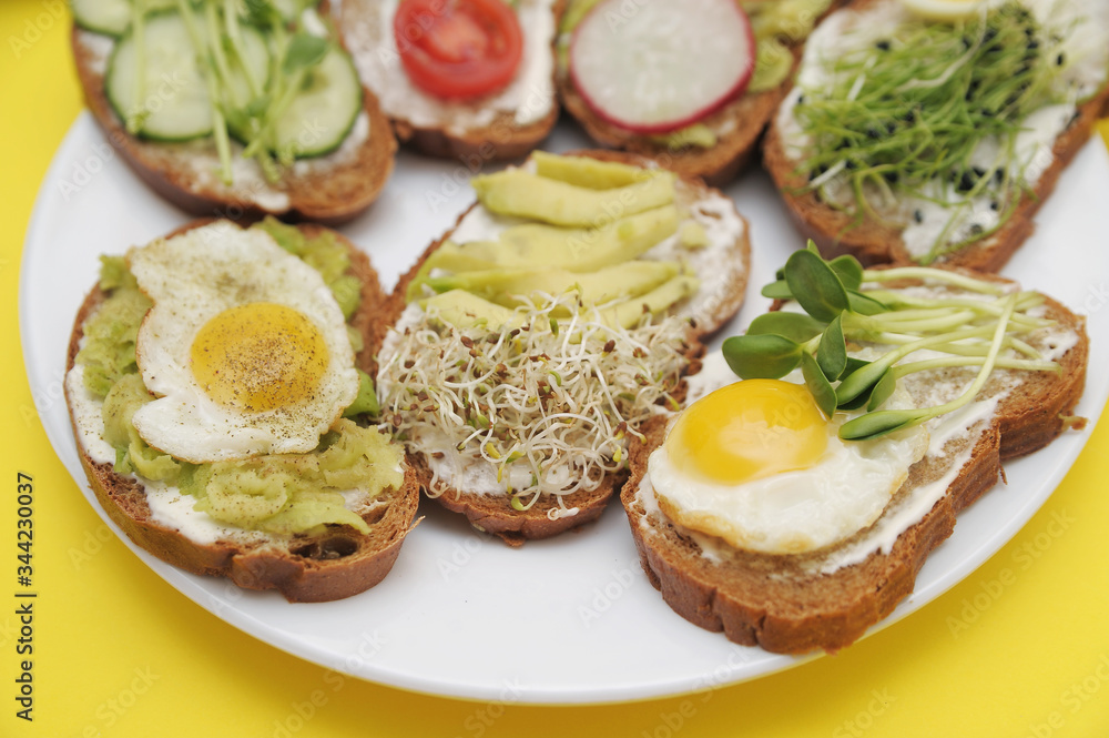 Sandwiches with vegetables, eggs, avokado and micro greens on stone background. Healthy food. Sandwiches with vegetables, eggs, avokado and micro greens on stone background. Healthy food.