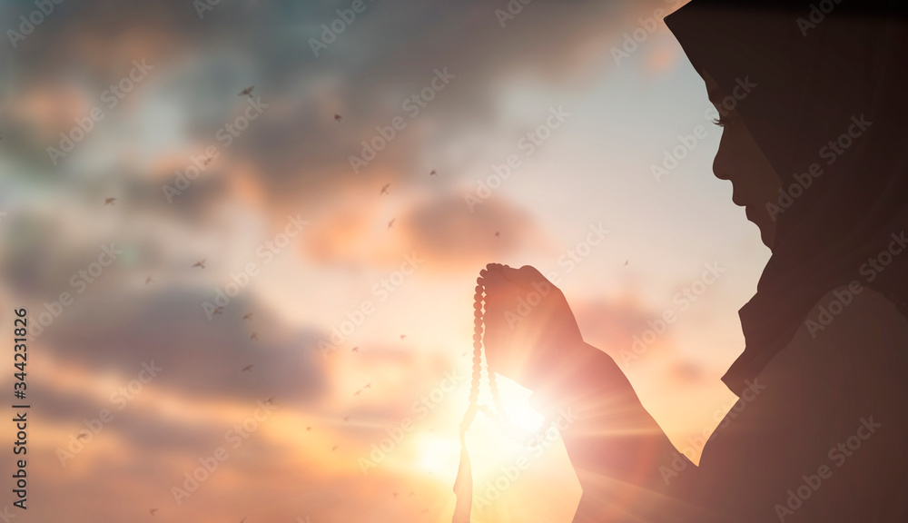 Young female muslim prayer with hijab praying to God front of white