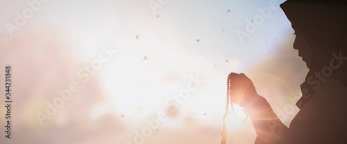 Young muslim woman prayer with hijab pray to God on blur mosque background concept for eid mubarak, life and soul fasting of international islamic ramadan sunlight photo