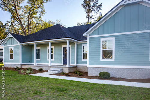 Front view of a brand new construction house with blue siding, a ranch style home with a yard © Ursula Page