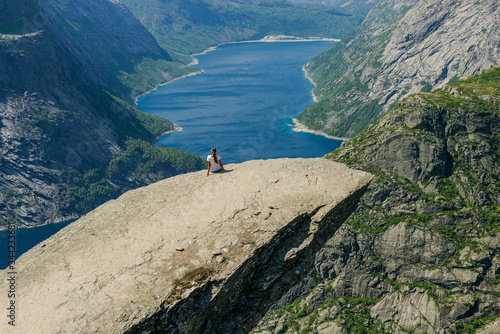 Trolltunga. Troll language in Norway. Rocky ledge above the fjord. Natural landmark of Norway. Girl sitting on the edge of a rocky cliff
 photo