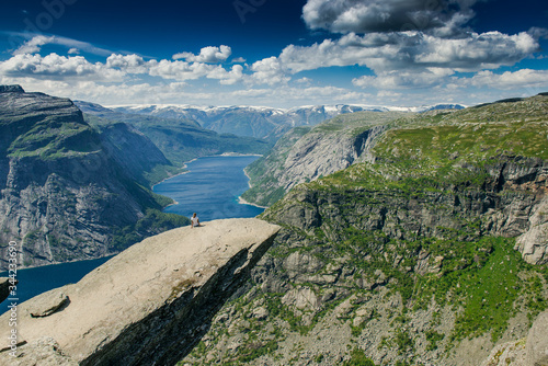 Trolltunga. Troll language in Norway. Rocky ledge above the fjord. Natural landmark of Norway. Girl sitting on the edge of a rocky cliff 